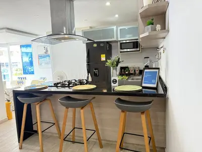 a kitchen with a counter with two bar stools and a laptop at A un Paso de la Playa in Cartagena de Indias