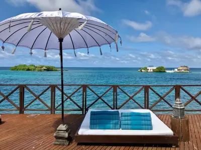 two chairs and an umbrella on a deck with the ocean at Isla Única- Islas del Rosario in Isla Grande