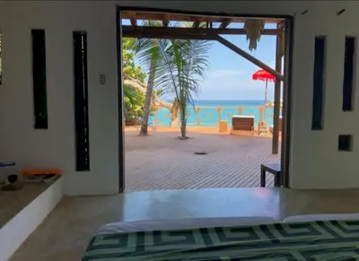 a bedroom with a door open to a view of the ocean at Isla Única- Islas del Rosario in Isla Grande
