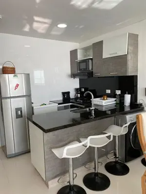 a kitchen with two bar stools and a refrigerator at Apartamento Frente al Mar in Cartagena de Indias