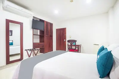 a bedroom with a large white bed with blue pillows at Ayenda Hotel Carivdi in Sincelejo