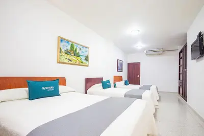 a hotel room with three beds and a tv at Ayenda Hotel Carivdi in Sincelejo