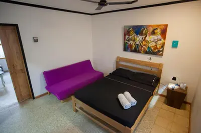 a small bedroom with a bed with a purple headboard at Hostal El Bando in Cartagena de Indias