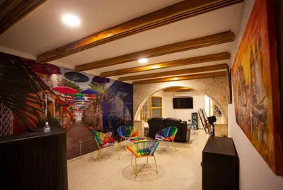 a room with colorful chairs and paintings on the walls at Hostal El Bando in Cartagena de Indias