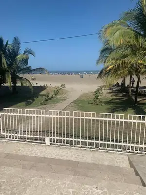 a white fence next to a beach with palm trees at Morros 922 una alcoba Edificio frente al mar in Cartagena de Indias