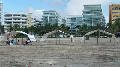 a group of tents on a beach with buildings at Morros 922 una alcoba Edificio frente al mar in Cartagena de Indias