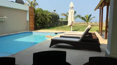a pool with two lounge chairs and an umbrella at Casa de Playa in Cartagena de Indias