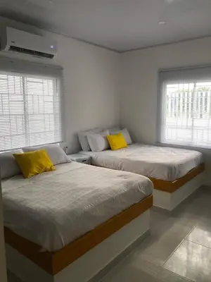 two beds in a room with two windows at Bahia Tropical Sandia Kiwi Piña in Coveñas