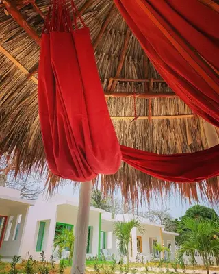 a red umbrella and a straw umbrella at Bahia Tropical Sandia Kiwi Piña in Coveñas