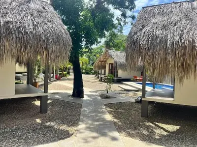a resort with two benches and a tree and a building at Anuk Glamping in San Bernardo del Viento