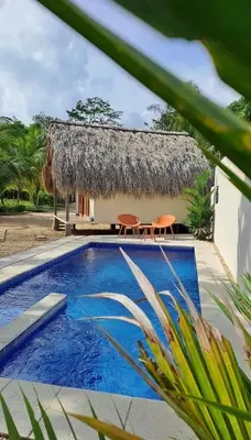 a villa with a swimming pool and a thatch roof at Anuk Glamping in San Bernardo del Viento