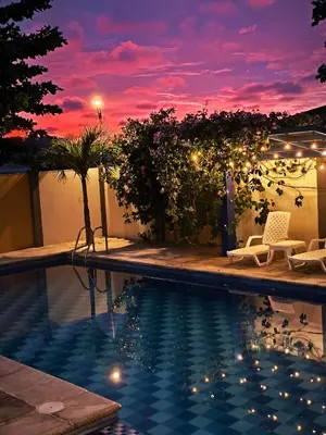 a resort swimming pool with a sunset in the background at Anuk Glamping in San Bernardo del Viento