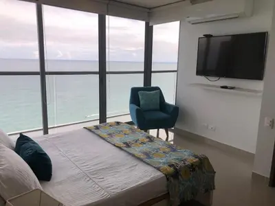 a bedroom with a bed and a chair and a television at Apartamentos frente al mar en Morros City in Cartagena de Indias