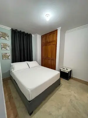 a bedroom with a white bed and a wooden cabinet at Hotel Marie Real Cartagena in Cartagena de Indias