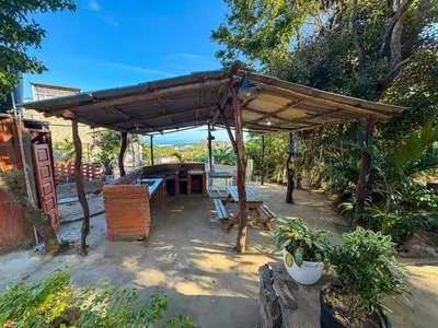 a wooden pavilion with a table and chairs under it at PALOMAR EcoCabaña in Santa Veronica