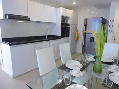 a kitchen with a glass table and white cabinets at Apartamento Mares de Cartagena in Cartagena de Indias