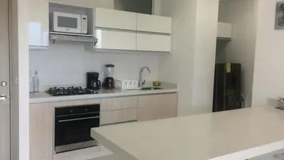 a white kitchen with a stove and a microwave at Hermoso Apto con vista a la sierra y a Cabo Tortuga en el sector del Irotama en Santa Marta in Gaira