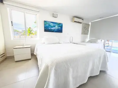 a white bedroom with two beds and a window at Quinta Del Mar El francés in Tolú
