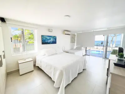 a white bedroom with a bed and a view of the ocean at Quinta Del Mar El francés in Tolú