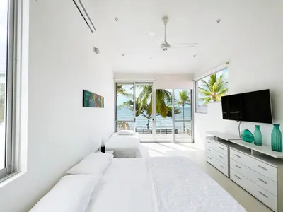 a white bedroom with two beds and a flat screen tv at Quinta Del Mar El francés in Tolú