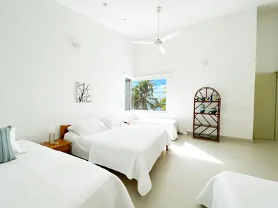a white room with four beds and a window at Quinta Del Mar El francés in Tolú