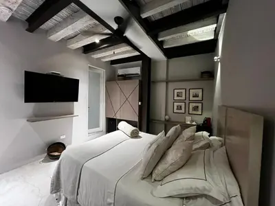 a bedroom with a large white bed and a flat screen tv at Lunalá Hotel Boutique in Cartagena de Indias