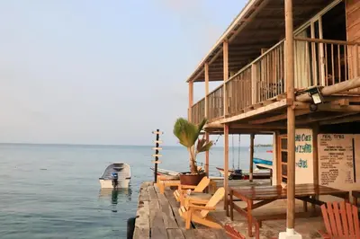 a house on the water with chairs and a boat at Hostel Santa Cruz del Islote in Santa Cruz del Islote