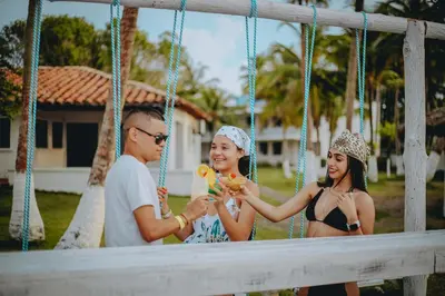 a man and two women sitting on a swing at Marbelo Coveñas by Bernalo Hotels in Coveñas