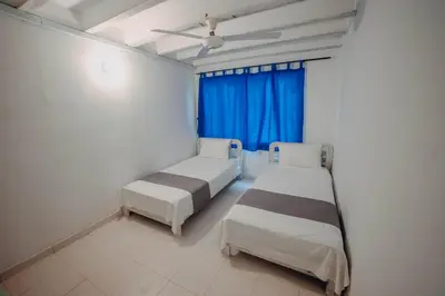 a bedroom with two beds and a blue window at Marbelo Coveñas by Bernalo Hotels in Coveñas