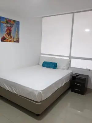 a bedroom with a white bed with a blue bag on it at Hotel ITACO in Cartagena de Indias