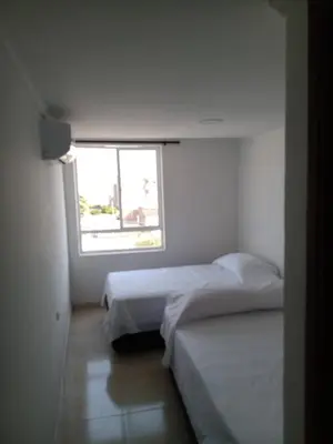 two beds in a small room with a window at HOTEL BOSQUE DE LAS AMERICAS in Cartagena de Indias