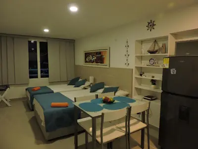 a living room with a bed and a table and a refrigerator at Estudio Loft Cartagena in Cartagena de Indias