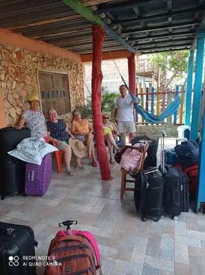 a group of people sitting on a porch with luggage at HOSTAL BELLEZA TROPICAL in Moñitos