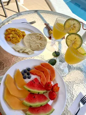 two plates of fruit on a table with glasses of juice at Hotel Corozal Plaza in Corozal