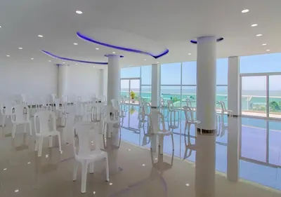 a room with white chairs and a pool at Playa Norte Hotel in Cartagena de Indias
