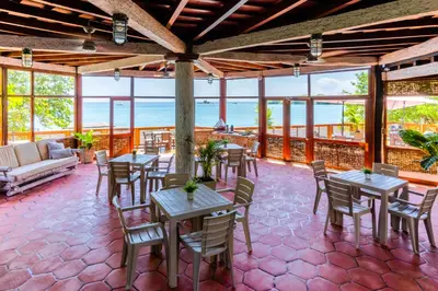 a patio with tables and chairs and the ocean at Rosario EcoHotel - Islas del Rosario in Isla Grande