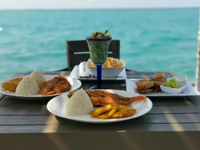 a table with three plates of food and a drink at Rosario EcoHotel - Islas del Rosario in Isla Grande
