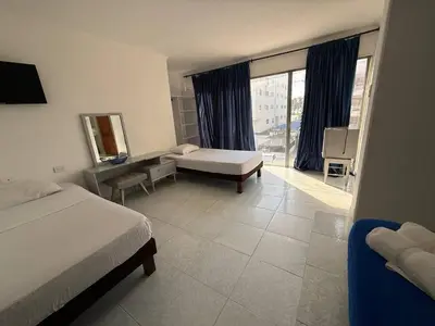 a bedroom with two beds and a desk and a window at Hotel Toledo FL in Cartagena de Indias