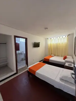 a hotel room with two beds and a television at Hotel Toledo FL in Cartagena de Indias