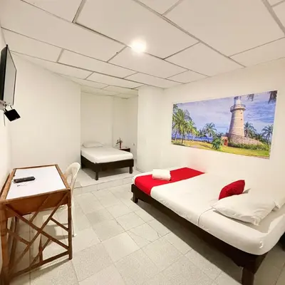 a bedroom with a bed and a desk and a table at Hotel Toledo FL in Cartagena de Indias