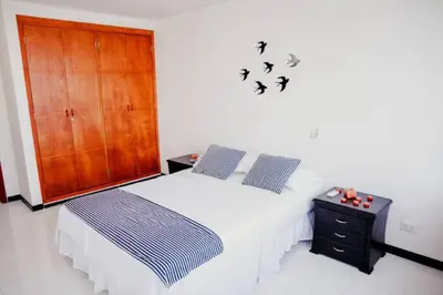 a bedroom with a bed and a cabinet and birds on the wall at Apartamento Lorenita in Cartagena de Indias
