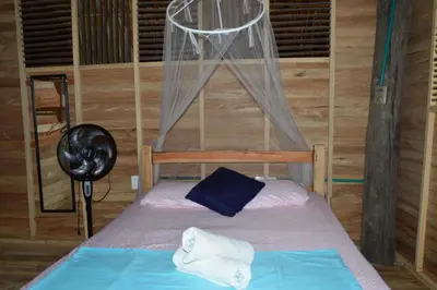 a bedroom with a bed and a fan at Palmar del viento cabaña frente al mar in Moñitos