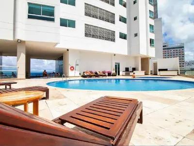 a swimming pool with benches and a building at Apartamento Palmetto Eliptic - Best Seaview in Cartagena de Indias