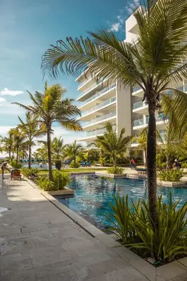 a resort swimming pool with palm trees and a building at MORROS EPIC 1 ALCOBA VISTA CIENAGA in Cartagena de Indias