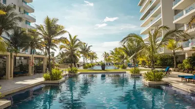 a swimming pool with palm trees and a building at MORROS EPIC 1 ALCOBA VISTA CIENAGA in Cartagena de Indias