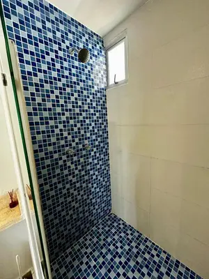 a bathroom with a shower with blue tiles on the wall at Apartamento con vista al mar piso 19 Bocagrande in Cartagena de Indias