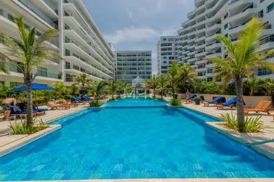 a large swimming pool with palm trees and buildings at Morros Epic 2 Bedrooms Beachfront by Inmobiliaria MFR in Cartagena de Indias