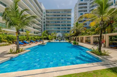 a large swimming pool with palm trees and buildings at Morros Epic 2 Bedrooms Beachfront by Inmobiliaria MFR in Cartagena de Indias