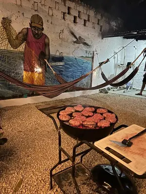a man standing next to a grill with food on a table at Mango Tree Hostel CTG 420 in Cartagena de Indias