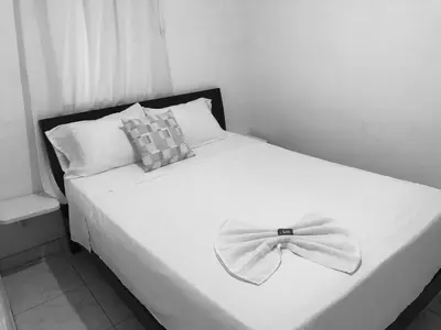 a white bed with a bow tie on it at Tita’s Airport Hotel in Cartagena de Indias